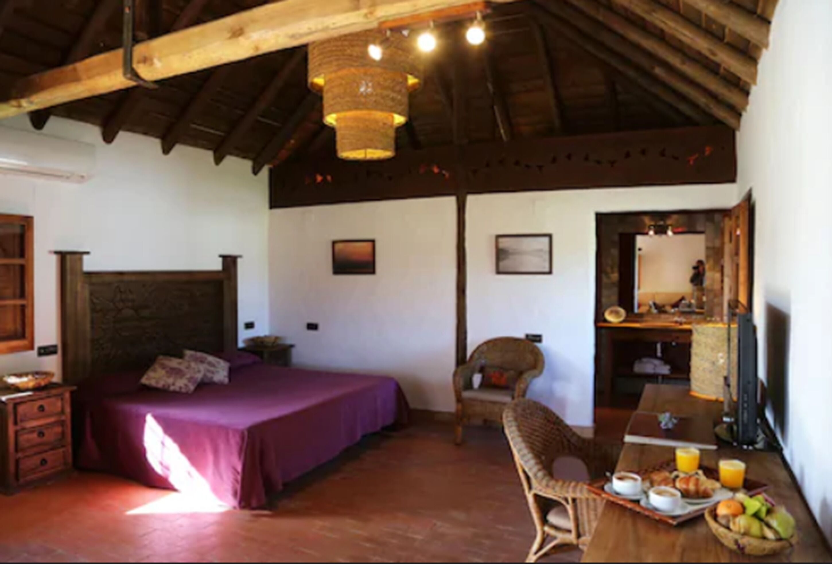 Un dormitorio con cama, una silla, una mesa de desayuno y un televisor.