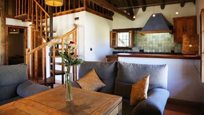 Un salón acogedor con una escalera de madera, una mesa de comedor con un jarrón de flores y una cocina con armarios de madera y salpicadero de azulejos.