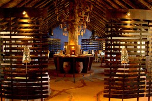 Une bibliothèque avec des étagères en bois et une table centrale ornée de poteries.