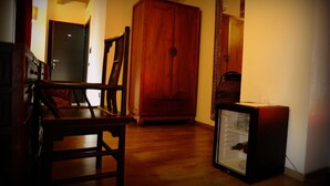 Ein Flur mit Holzboden, einem Holzschrank, einem kleinen Kühlschrank und einer Tür zu einem weiteren Raum.