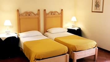 Ein Hotelzimmer mit zwei Einzelbetten, jeweils mit einem Holz-Kopfteil, weißer Bettwäsche und einer gelben Tagesdecke. Es gibt zwei Nachttische mit Lampen und ein gerahmtes Bild an der Wand.