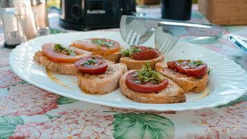 Un piatto di bruschette con pomodori e erbe aromatiche su una tovaglia a fiori.