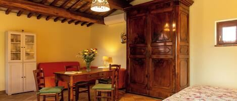 Un coin repas avec une table et des chaises en bois, un buffet et une couvre-lit à motifs floraux.