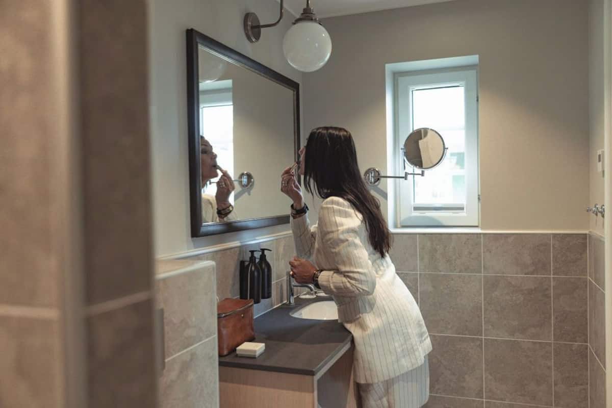 A bathroom with a large mirror, a sink, and a window.