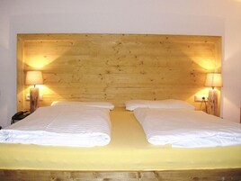 Una cama doble con cabecera de madera, dos lámparas de noche y un teléfono al lado izquierdo.