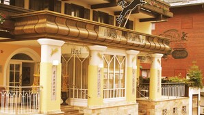 Um hotel com fachada clássica, destacando uma entrada imponente com escadaria que leva à entrada principal.
