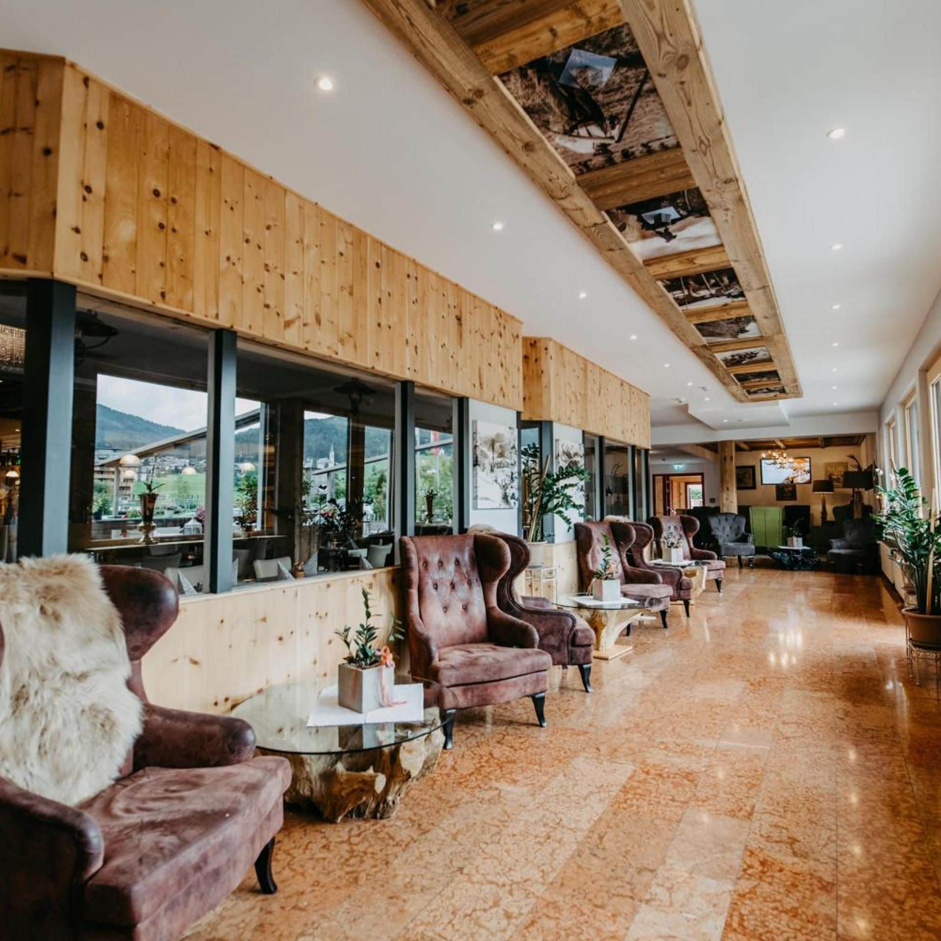 Un hall d’hôtel avec des boiseries, des fauteuils en cuir et de grandes fenêtres donnant sur l’extérieur.