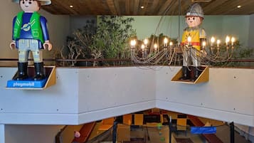Un espace de jeux pour enfants avec une figurine Playmobil, un luminaire suspendu et une vue sur le niveau inférieur.