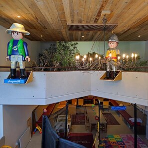 A children's play area with a playmobil figure, a hanging light fixture, and a view of the lower level. - Vitalhotel Gosau (Gosau)