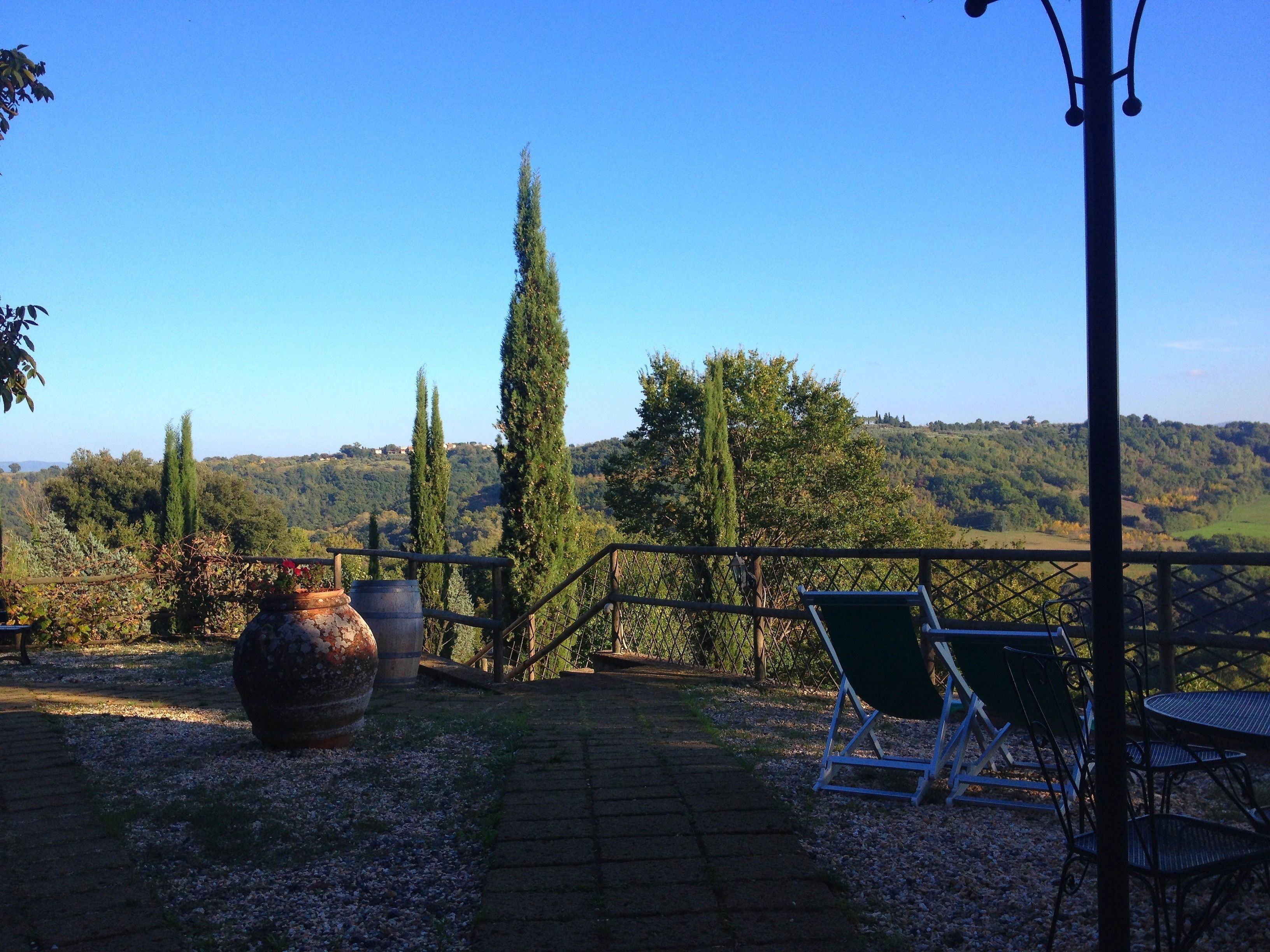 Un patio con vistas a un paisaje montañoso, una maceta de piedra grande y mobiliario exterior.