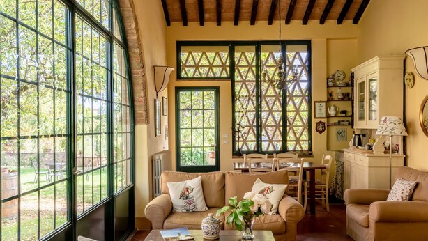 Una sala acogedora con ventanas amplias, un comedor y una cocina.