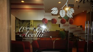 A modern interior with red sofas, a white coffee table, and decorative leaf patterns on the ceiling. - Hostal Acella (Pamplona)