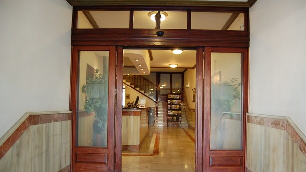A grand entrance with a wooden door and glass panels, leading to a staircase and a reception area. - Hotel Marina Victoria (Algeciras)