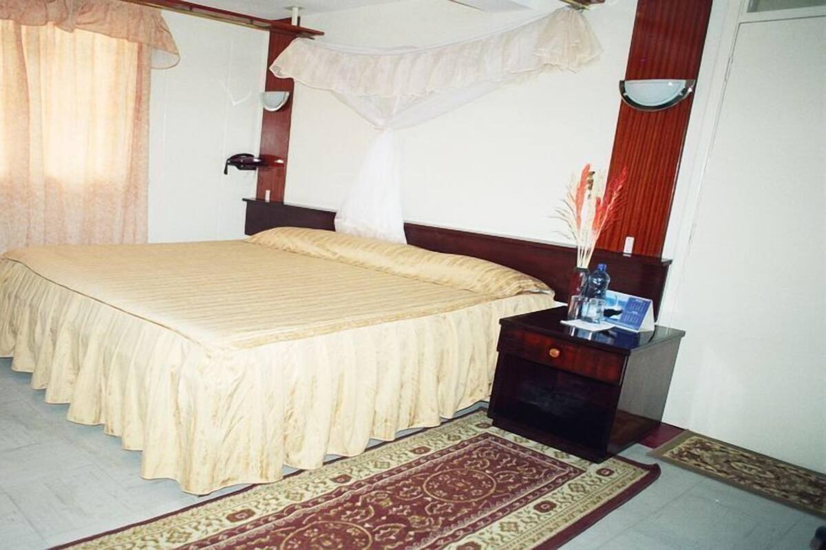 A bedroom with a bed, nightstand, and a decorative rug.