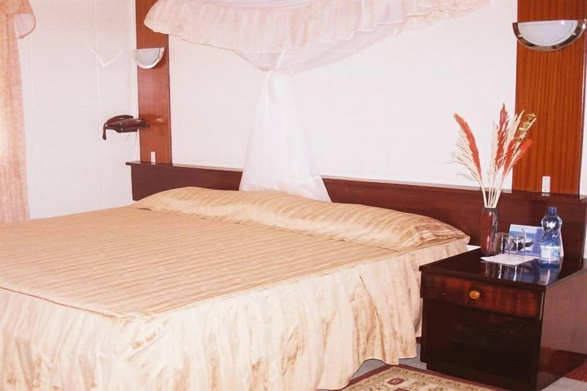 A hotel room with a bed, bedside table, and a nightstand.