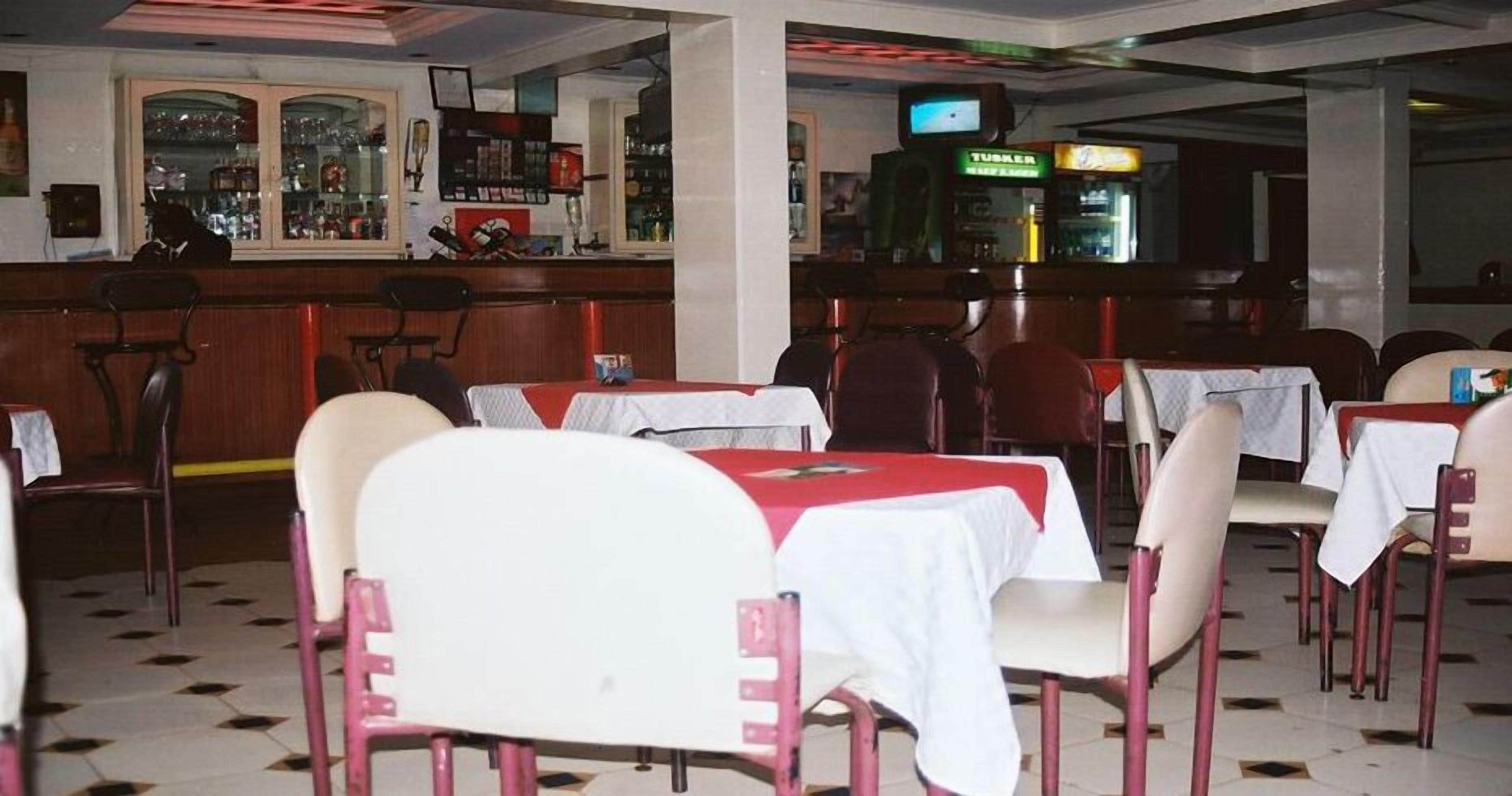 Ein Restaurant mit Tischen, Stühlen, einer Bar und einem Fernsehbildschirm.