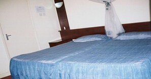 A single bed with a canopy, a wooden headboard, and a white door with a handle. - Blue Hut Hotel (Nairobi)