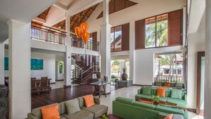 A spacious lobby with a staircase, green and beige sofas, and a wooden coffee table. - Blue Ocean Resort (Mui Ne)