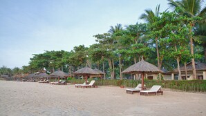 A beach resort with thatched-roof huts, lounge chairs, and palm trees. - Blue Ocean Resort (Mui Ne)