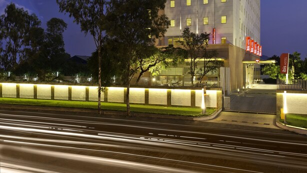 A modern hotel with a prominent "ibis HOTEL" sign, multiple floors, and a well-lit entrance. - ibis Nashik Hotel (Nashik)