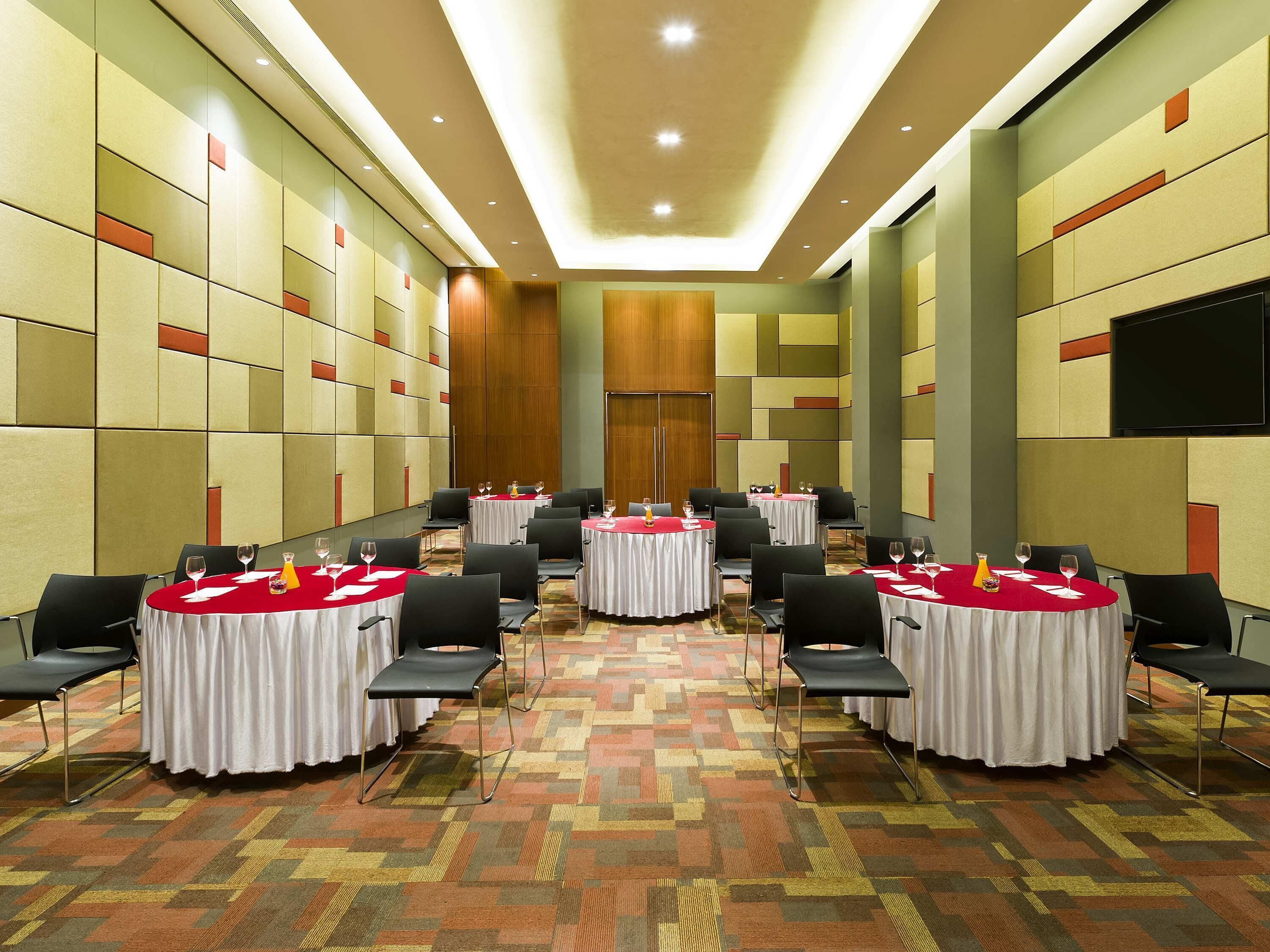 A conference room with round tables, chairs, and a carpeted floor.