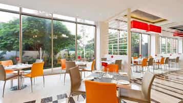 A modern dining area with large windows, a checkered floor, and orange chairs.
