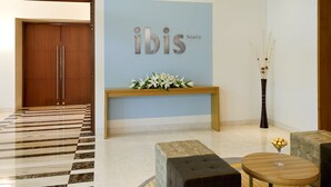 A modern lobby with a checkered floor, a reception desk, and a seating area with a round table and ottoman. - ibis Nashik Hotel (Nashik)