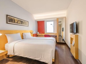Une chambre d’hôtel avec deux lits, un bureau, une télévision et une fenêtre.