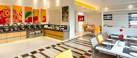A hotel lobby with a buffet, dining area, and artwork on the walls.