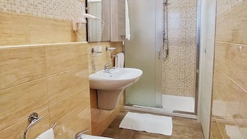 A bathroom with a shower, two sinks, a toilet, and a mirror.