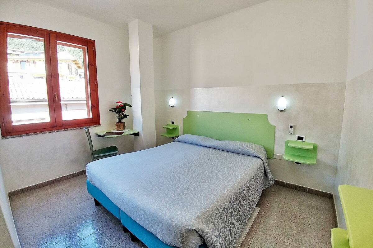 A bedroom with a bed, a window, a bedside table, and a nightstand.