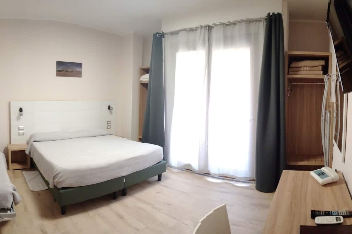 A hotel room with a bed, a desk with a telephone, and a wardrobe.