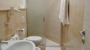 A bathroom with a large sink, toilet, and glass shower enclosure.