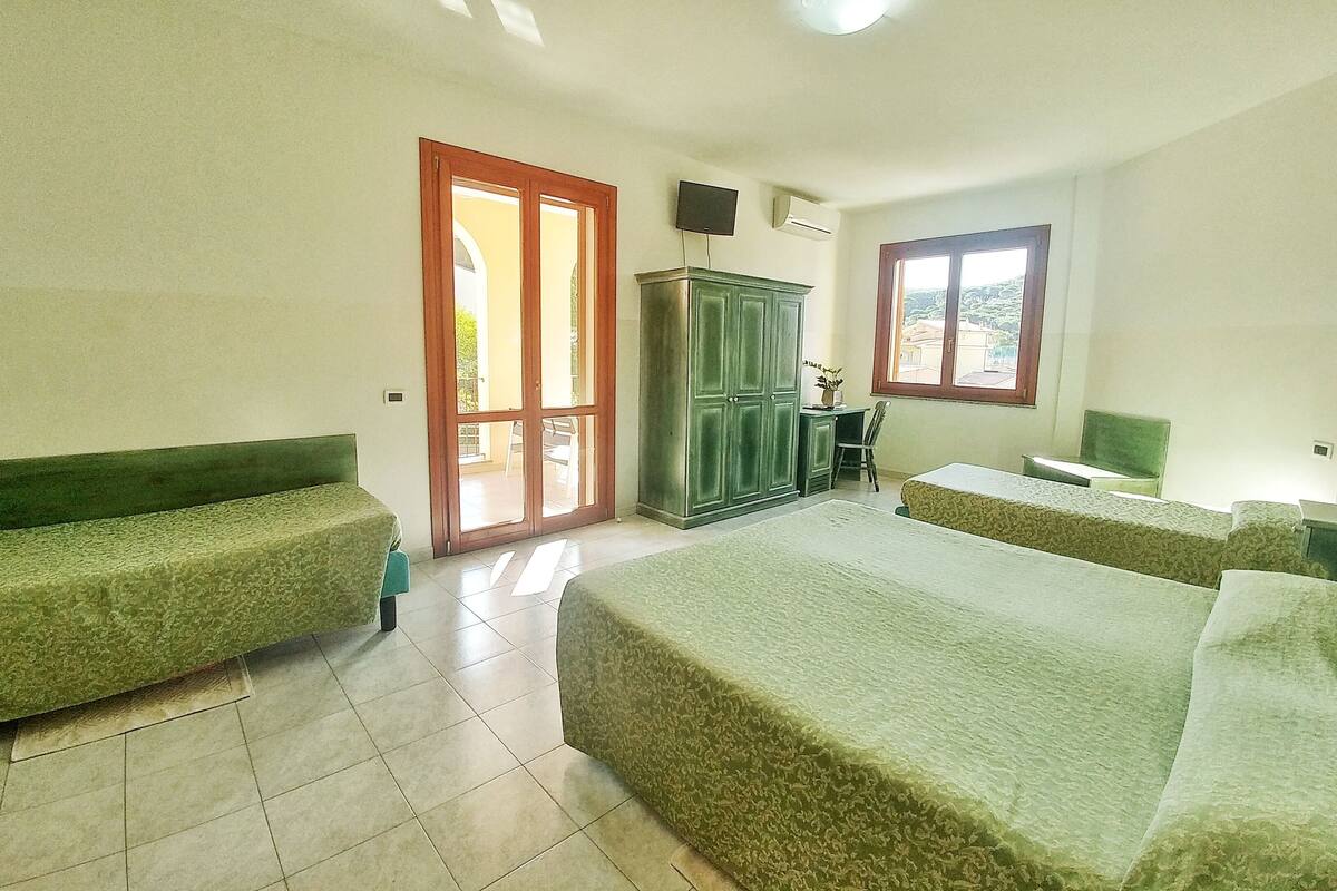 A room with two beds, a desk, a chair, a wardrobe, and a television.