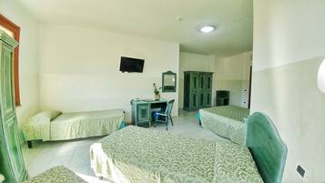 A room with two single beds, a desk with a chair, a television, and a wardrobe.