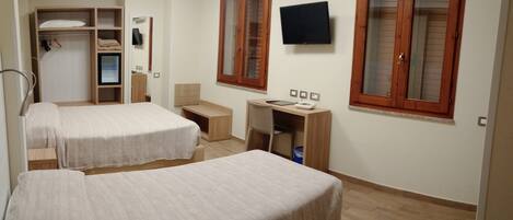 A hotel room with two beds, a desk, a chair, a TV, and a wardrobe.