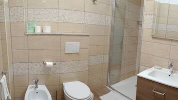 Een moderne badkamer met een hygiëneschuimer, toilet en een douche met glazen wanden.