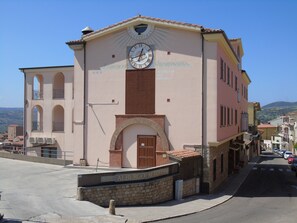 A building with a clock, a sign reading "Albergo Meridiana," and a view of the surrounding area.