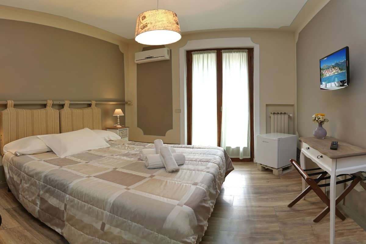A bedroom with a bed, bedside tables, a desk, and a radiator.