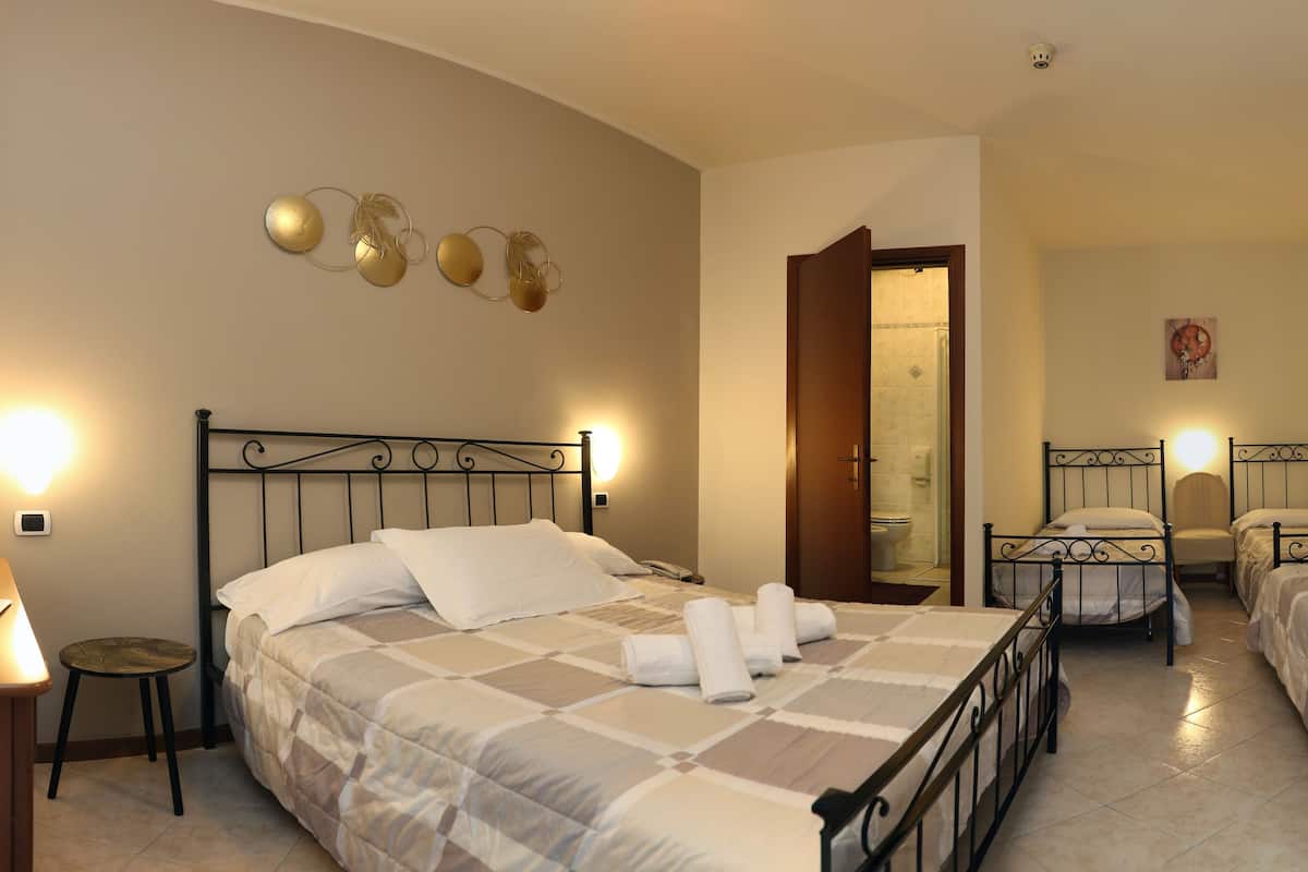 A hotel room with two beds, a desk, a chair, and a bathroom visible through an open door.