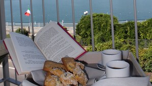 A balcony with a view of a lake, a book, and a tray with pastries and cups. - Capovilla (Pisogne)