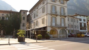 A hotel with a ground-floor café, a covered outdoor seating area, and a view of the mountains. - Capovilla (Pisogne)
