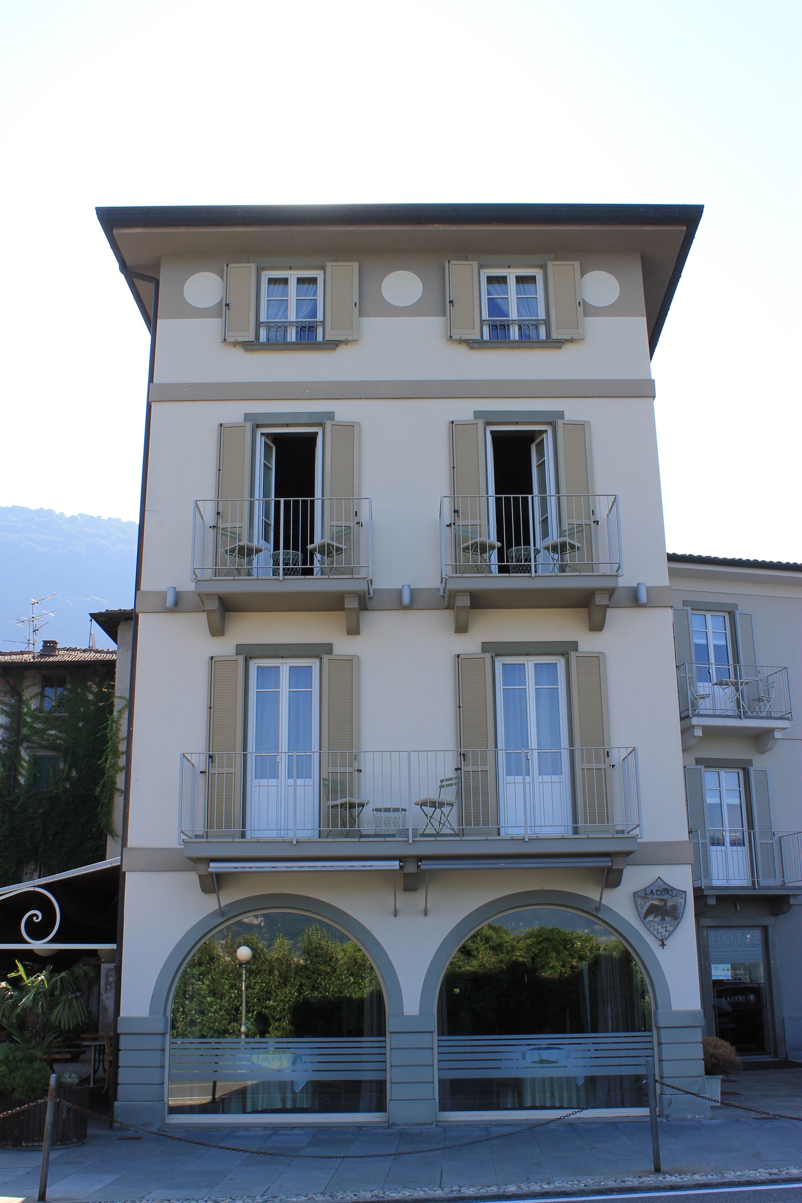 Un edificio de varios pisos con balcones, un arco central y un portón con cadena.