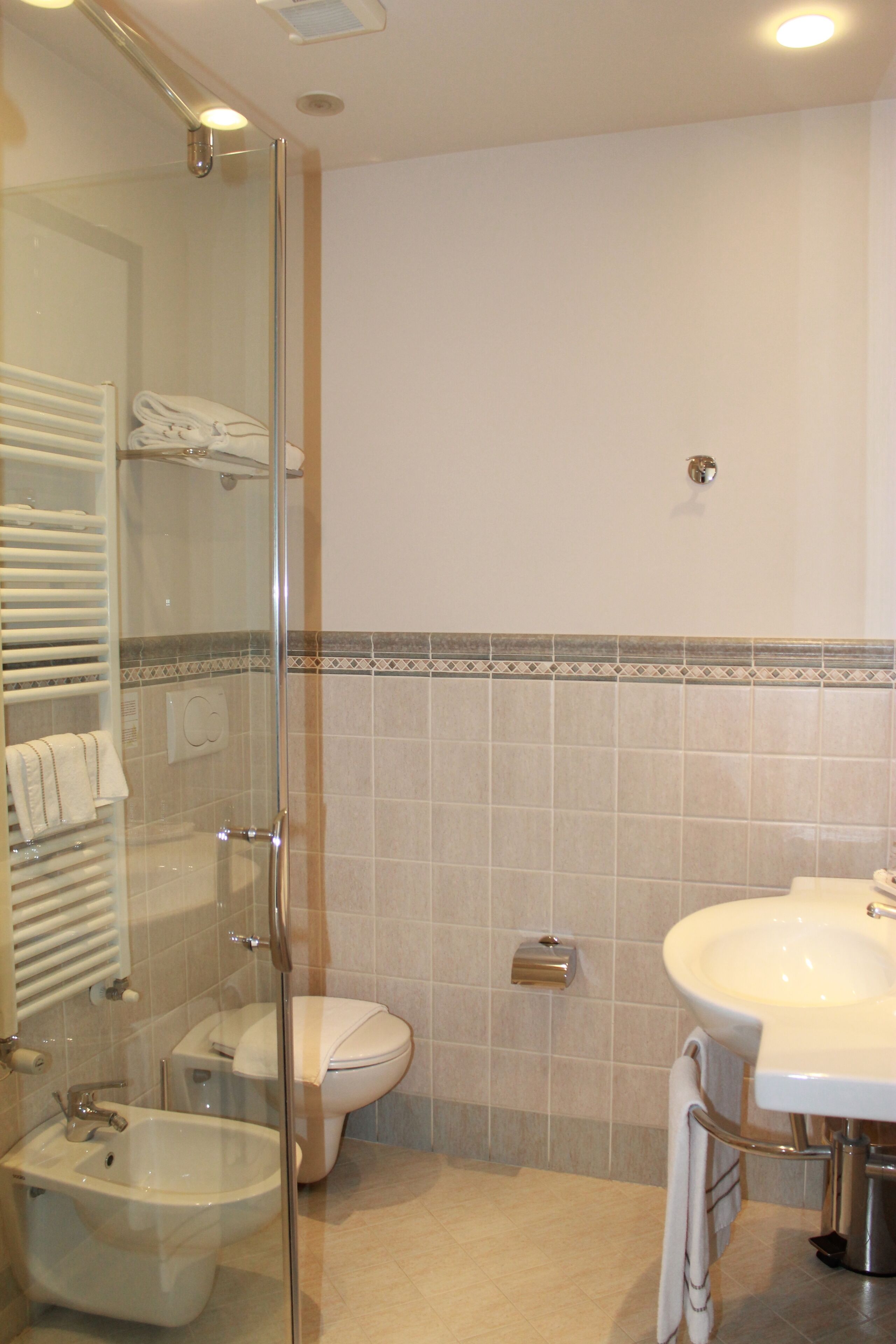 A bathroom with a glass-enclosed shower, a white sink, and a toilet.