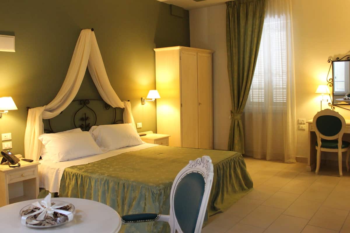A hotel room with a bed, a desk, a chair, a wardrobe, and a bathroom.