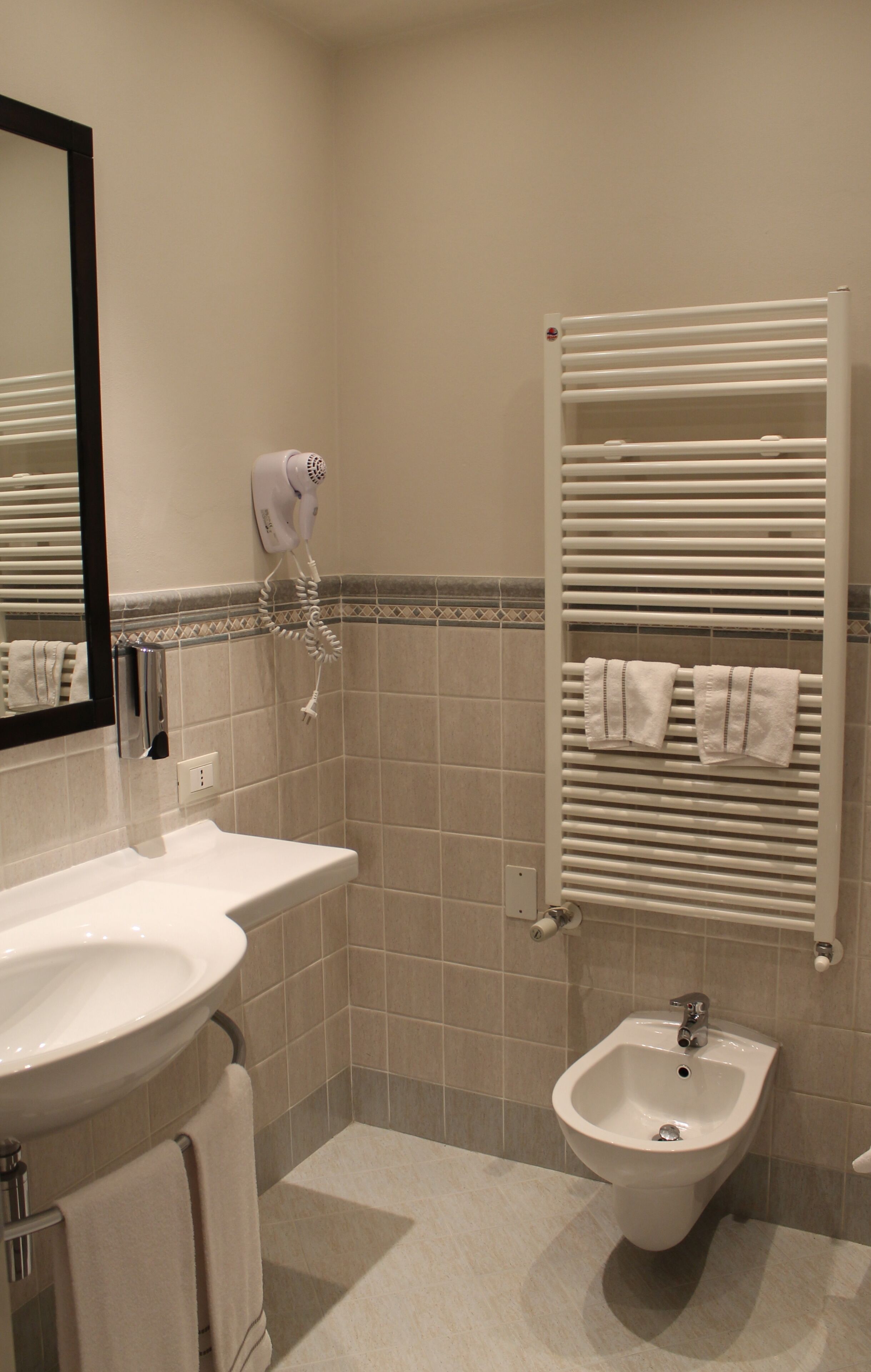 Une salle de bain équipée d’un lavabo, d’un bidet, d’un porte-serviettes et d’un sèche-cheveux.
