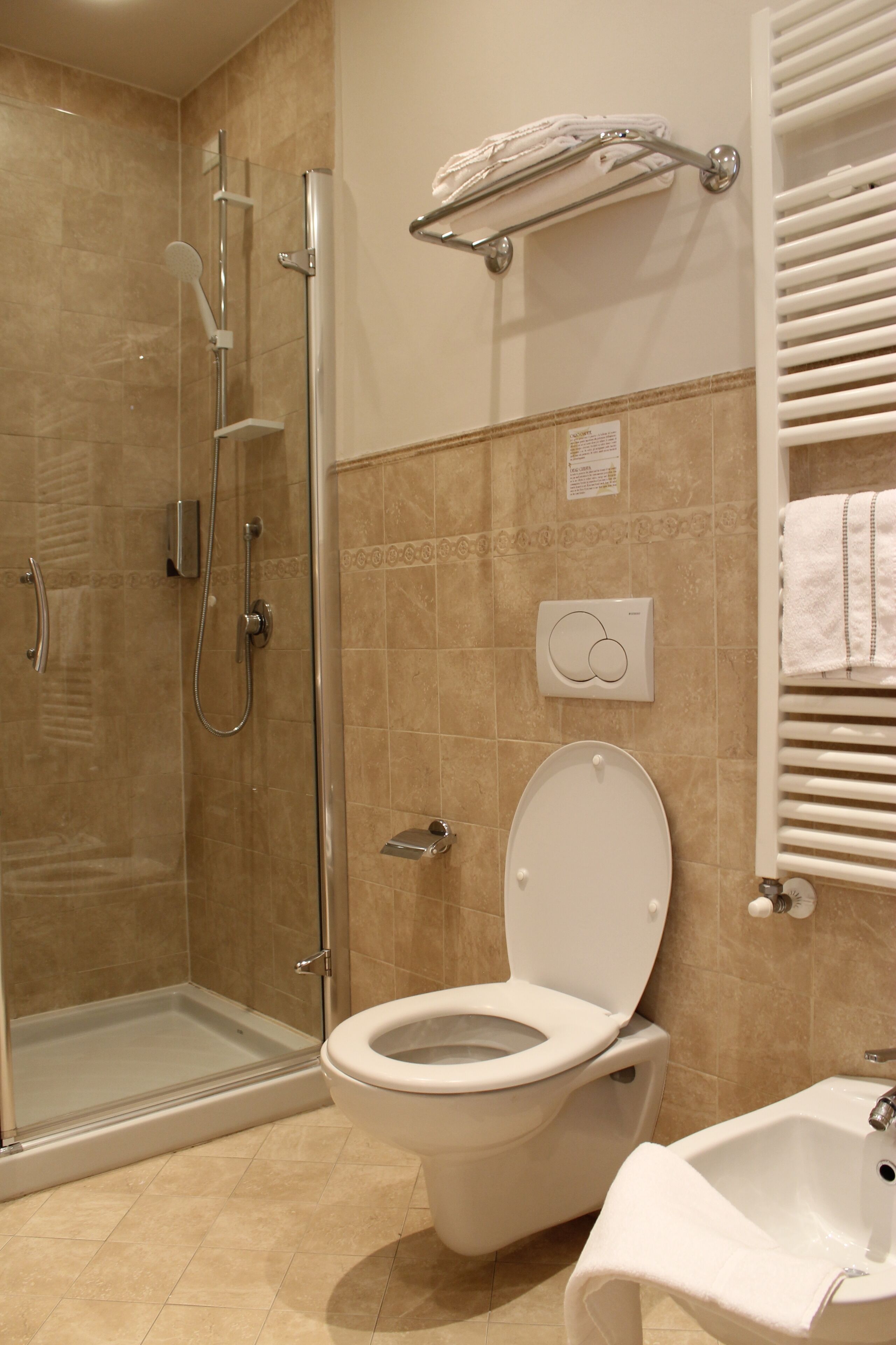A bathroom with a glass-enclosed shower, a toilet, a sink, and a towel rack.