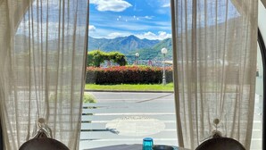 A table set for two with a view of mountains and a clear sky through sheer curtains. - Capovilla (Pisogne)
