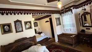 A traditional room with a large bed, a wooden headboard, a small table, and a mirror. - Hotel Nilya - Special Class (Selçuk)