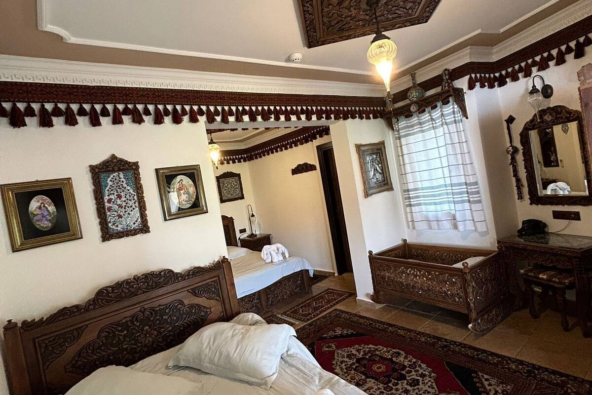 Una habitación tradicional con una cama grande, un cabecero de madera, una mesita pequeña y un espejo.